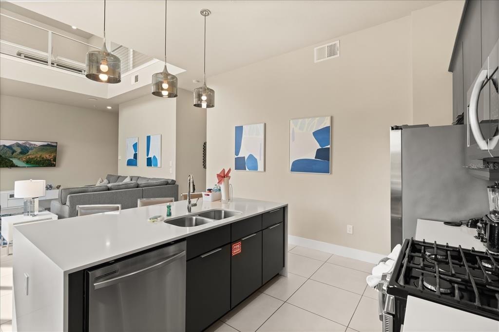 A modern kitchen features a white island with a sink, dark cabinets, and stainless appliances — 7770 SANDY RIDGE DRIVE 218 BLDG 28 With Elevator, KISSIMMEE, FL