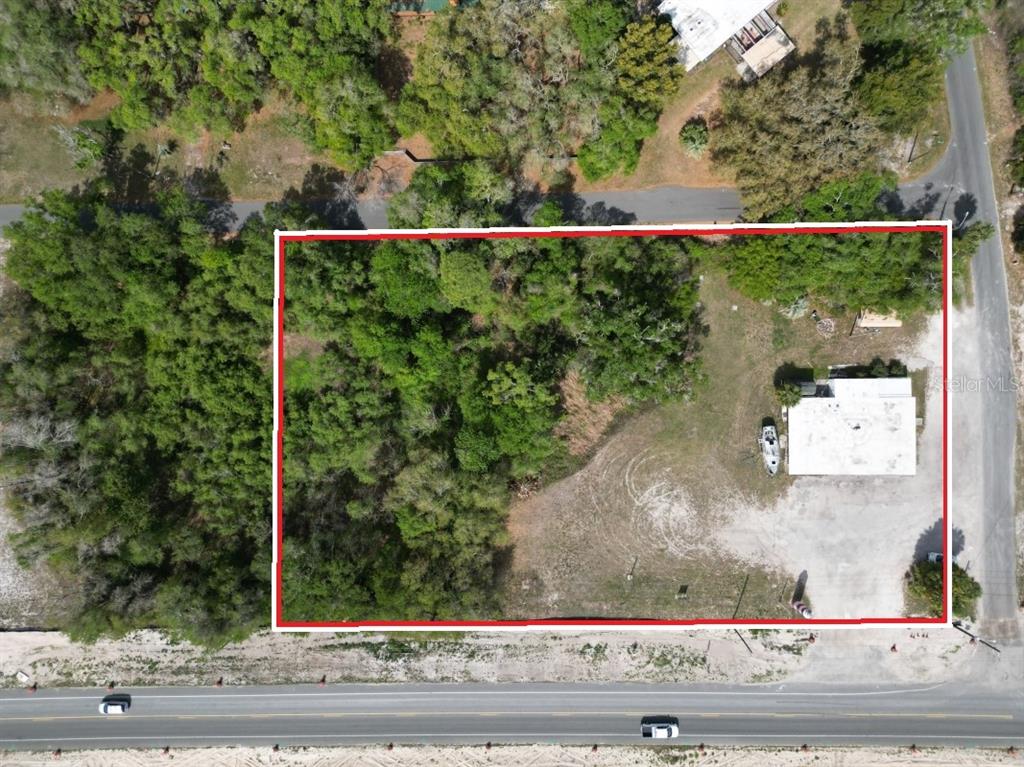 An aerial view shows a rectangular lot with trees, a building, and a paved road — 5025 TREIMAN BOULEVARD, DADE CITY, FL