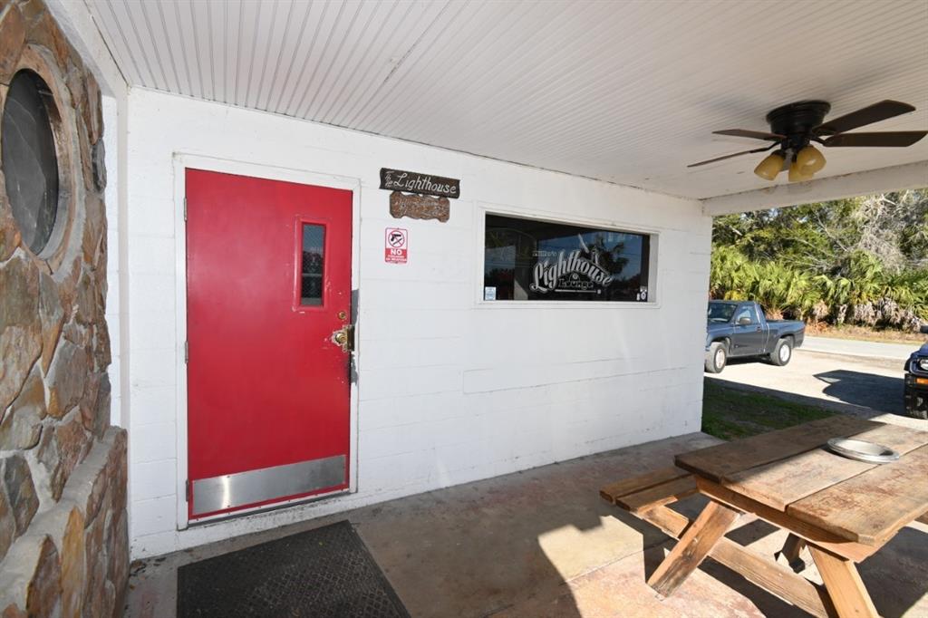 A red door and a wooden picnic table are on the covered porch of a building — 5025 TREIMAN BOULEVARD, DADE CITY, FL