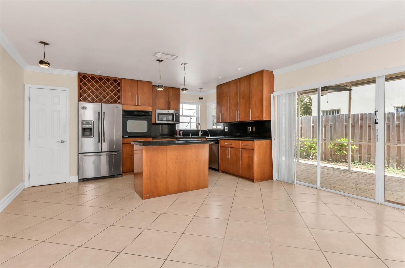 A kitchen features wood cabinets, stainless steel appliances, a center island, and sliding glass doors — 5486 NW 44th Way, Coconut Creek FL 33073, COCONUT CREEK, FL