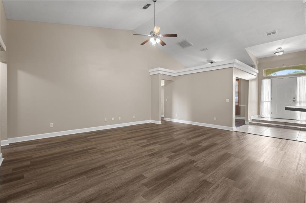 A spacious living room features vaulted ceilings, wood-look flooring, and an entryway with tiled steps — 5320 SW 115TH LOOP, OCALA, FL