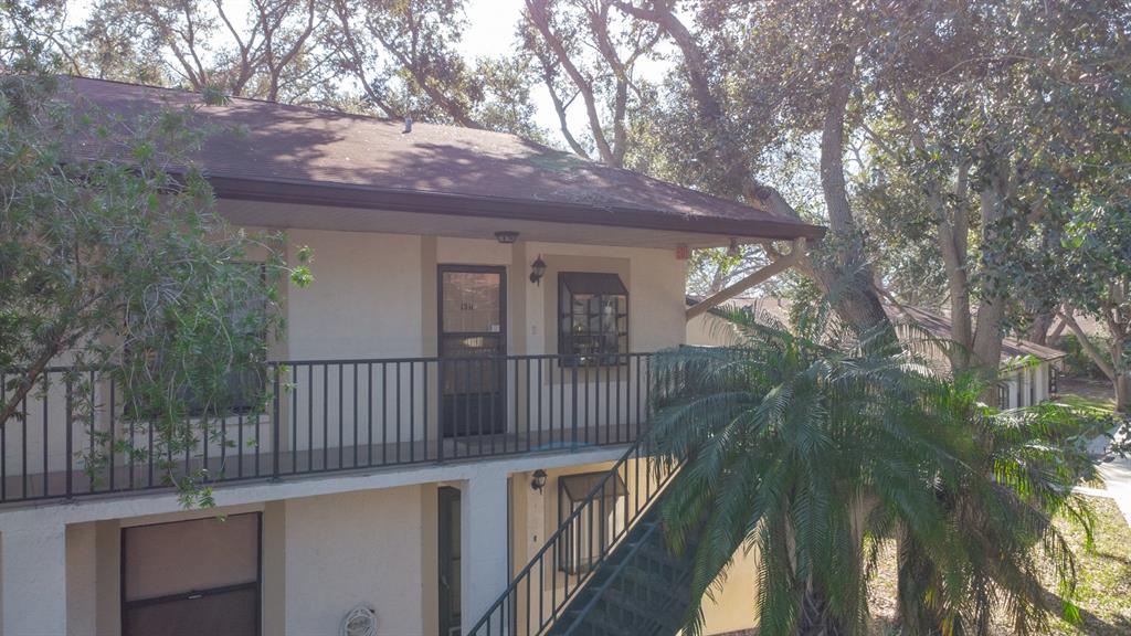 An exterior view of a two-story apartment building with a balcony and metal staircase — 11511 113TH STREET UNIT 13H, LARGO, FL