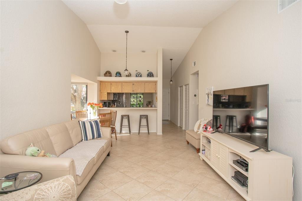 A living room with tile floors, a beige sofa, and a television on a white stand — 11511 113TH STREET UNIT 13H, LARGO, FL