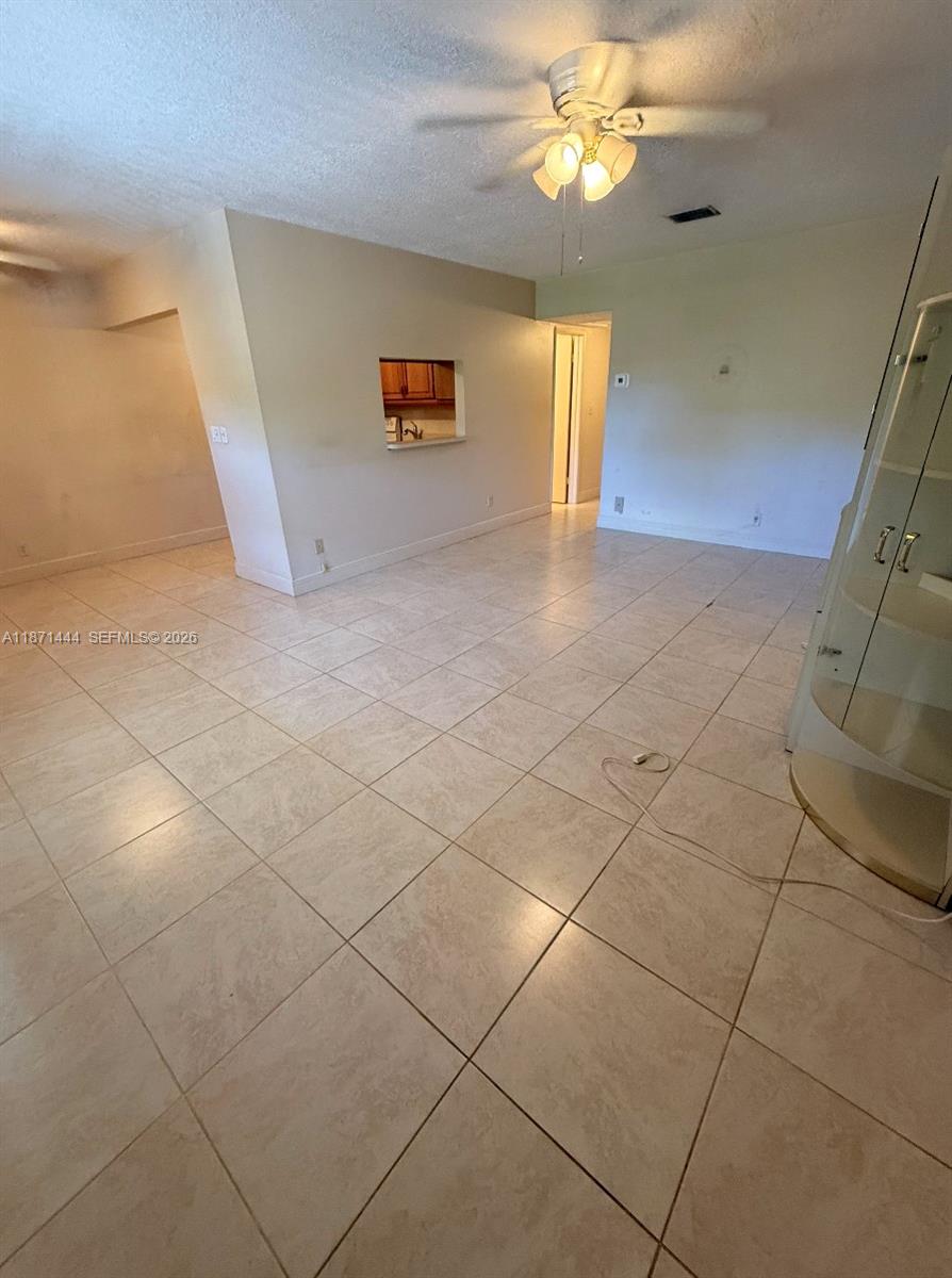 An open living area features light-colored tile flooring, a ceiling fan, and a kitchen pass-through — 2905 Pierce St # 17, Hollywood FL 33020, HOLLYWOOD, FL