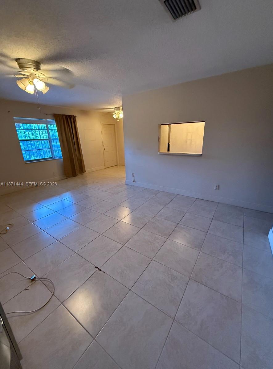An empty living room features light-colored tile flooring, a ceiling fan, and a pass-through window — 2905 Pierce St # 17, Hollywood FL 33020, HOLLYWOOD, FL