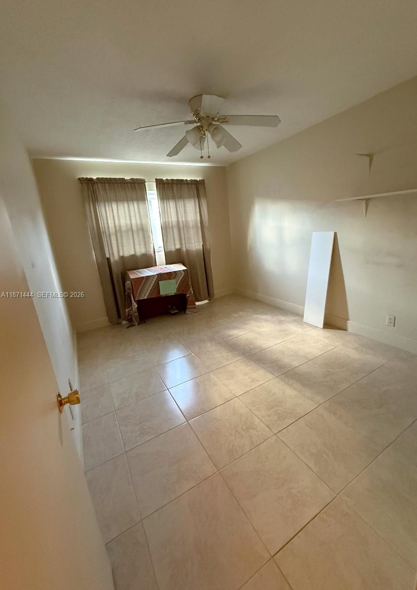 A bedroom with beige walls, tile flooring, a ceiling fan, and a window with curtains — 2905 Pierce St # 17, Hollywood FL 33020, HOLLYWOOD, FL