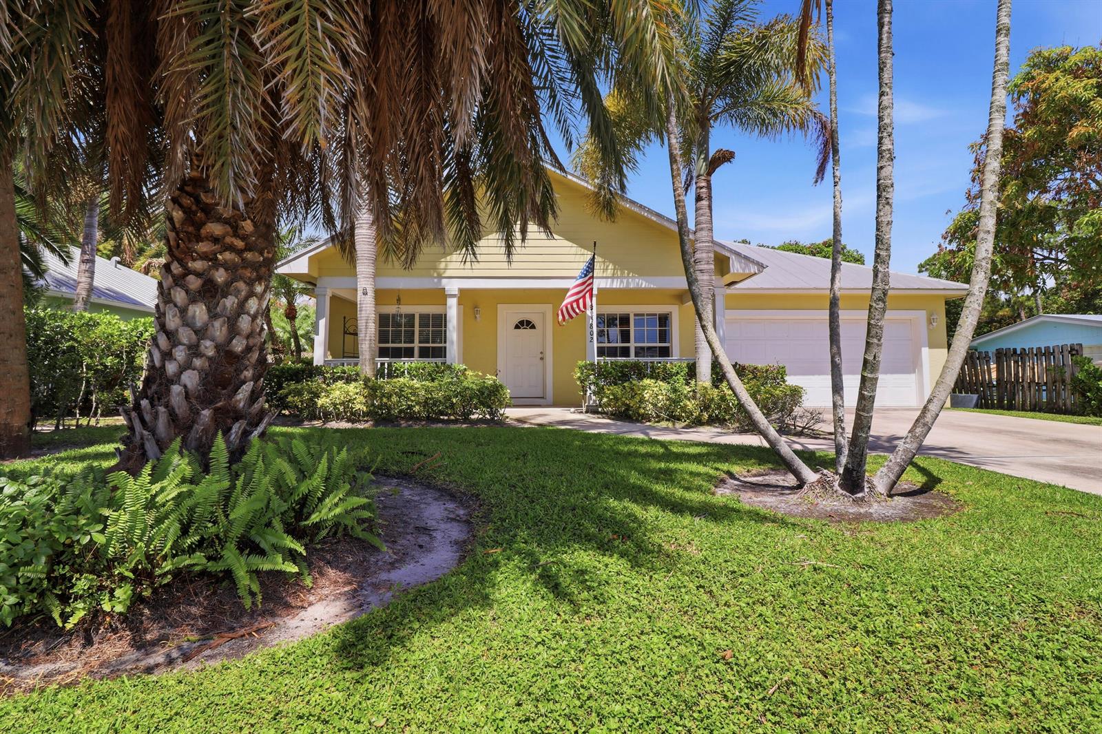 A yellow single-story house with a white garage and palm trees in the front yard — 5802 SE Wesley Avenue, Stuart FL 34997, STUART, FL