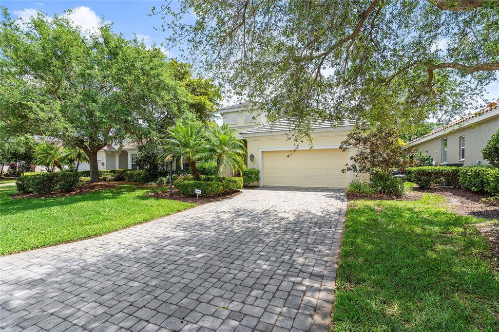 A single-story house with a paved driveway, a two-car garage, and mature landscaping — 8416 ABINGDON COURT, UNIVERSITY PARK, FL