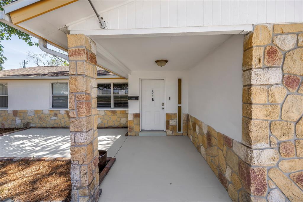 A single-story house with a stone facade, a white garage door, and a concrete driveway — 518 62ND AVENUE NE, ST PETERSBURG, FL