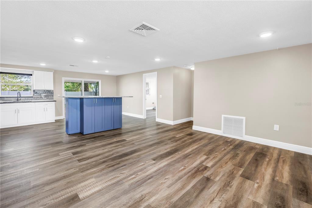 A spacious open-concept kitchen and living area with wood-look flooring and a blue island — 518 62ND AVENUE NE, ST PETERSBURG, FL