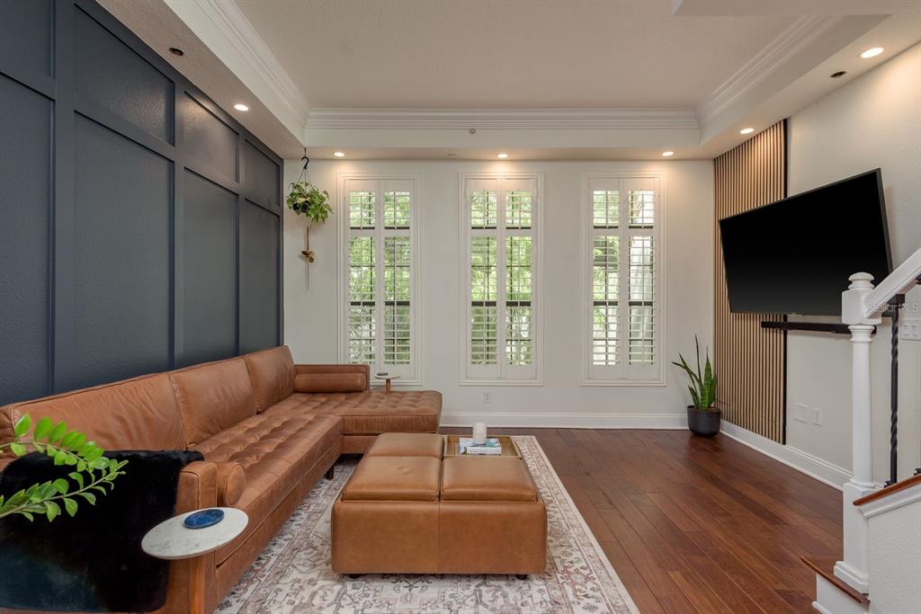 A living room features a dark blue accent wall, leather sectional, and wood slat wall — 2221 SOHO BAY COURT, TAMPA, FL