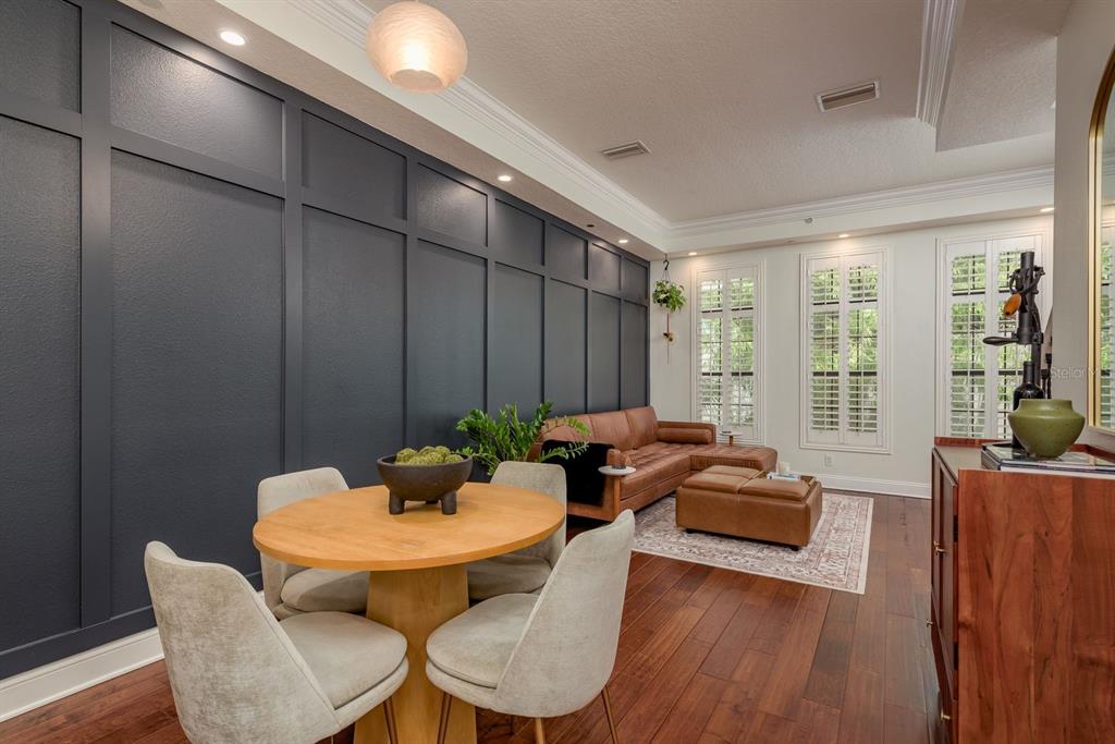A dining and living area features a dark blue paneled wall, wood floors, and furniture — 2221 SOHO BAY COURT, TAMPA, FL