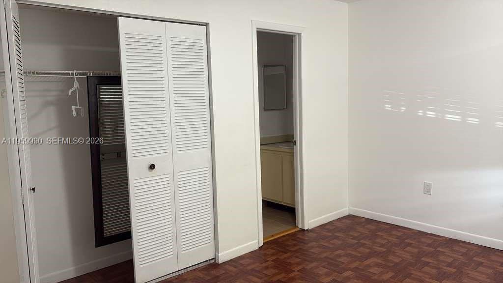 A bedroom features a closet with louvered doors, parquet flooring, and an adjacent bathroom doorway — 6911 SW 129 AV # 5, Miami FL 33183, MIAMI, FL