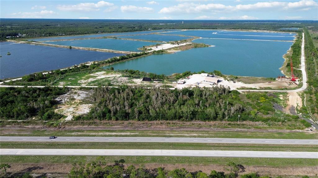 An aerial view shows a large industrial quarry with multiple ponds and a highway nearby — 16540 TAMIAMI TRAIL, PUNTA GORDA, FL