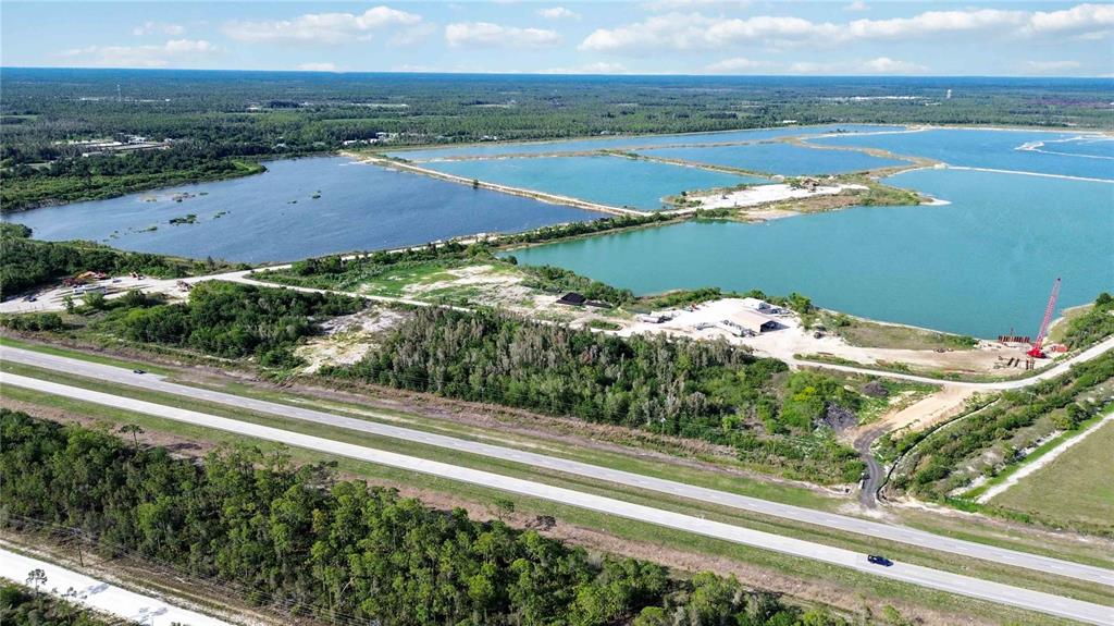An aerial view shows a highway running past a large industrial site with water-filled basins — 16540 TAMIAMI TRAIL, PUNTA GORDA, FL