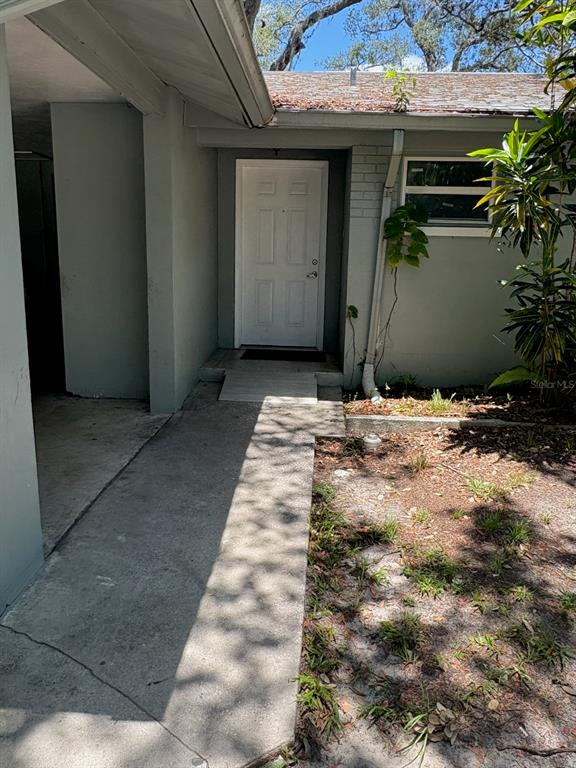 A concrete walkway leads to the white front door of a gray single-story house — 439 E MARTIN LUTHER KING JR DRIVE, TARPON SPRINGS, FL