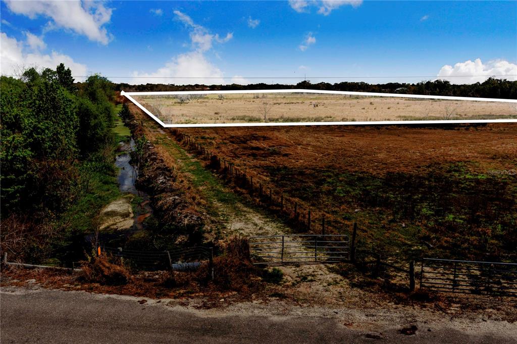 An elevated view shows a fenced, grassy field bordered by a ditch and trees — 3705 HIGH STREET, WINTER HAVEN, FL