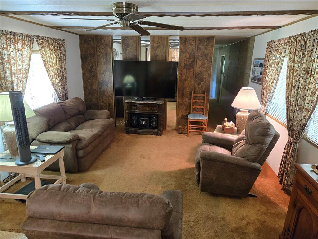 A living room features brown carpet, wood-paneled walls, a ceiling fan, and brown upholstered furniture — 560 NE 62ND TERRACE, OCALA, FL