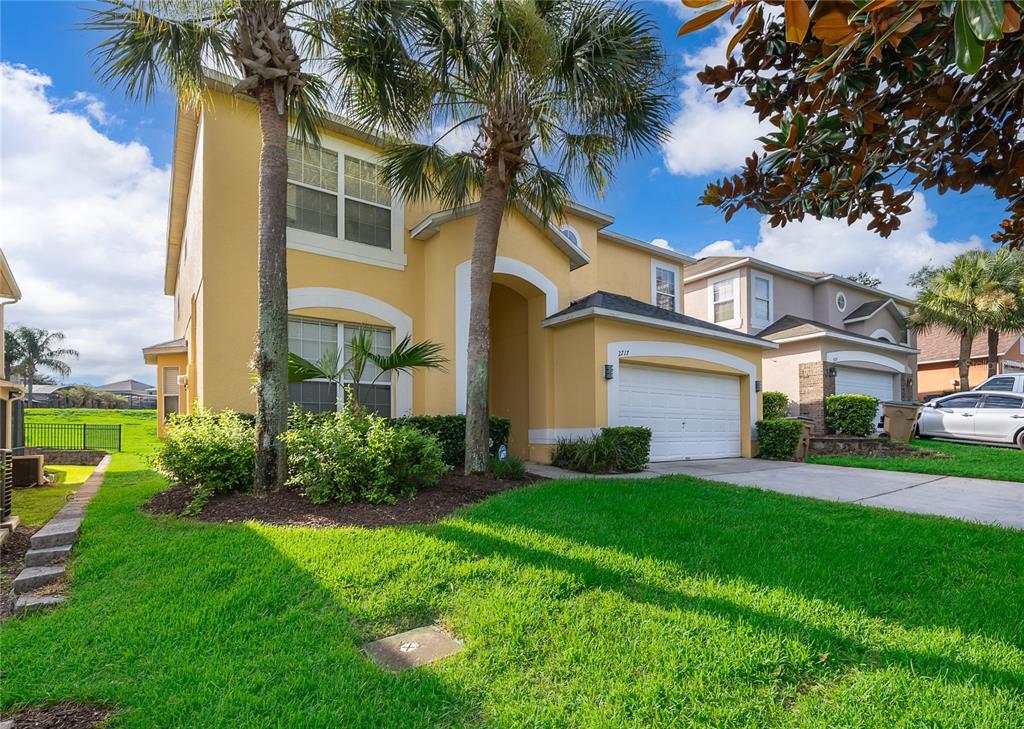 A two-story yellow house with a two-car garage and palm trees in the front yard — 2717 FIESTA KEY DRIVE, KISSIMMEE, FL