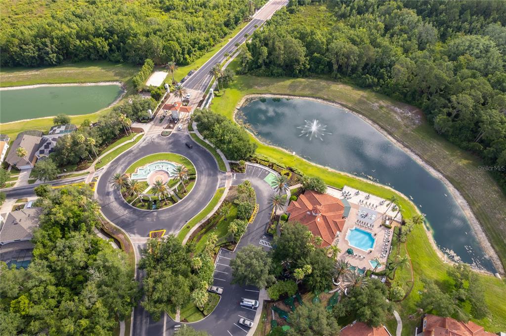 An aerial view shows a residential community entrance with a roundabout, pond, and clubhouse — 2717 FIESTA KEY DRIVE, KISSIMMEE, FL