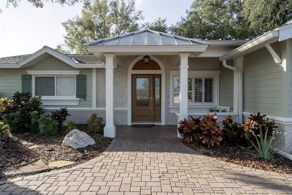 A front exterior view of a house with a brick walkway and a covered entryway — 378 WESTWINDS DRIVE, PALM HARBOR, FL