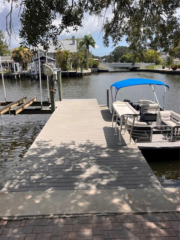 A wooden dock extends into a canal with a pontoon boat moored alongside — 378 WESTWINDS DRIVE, PALM HARBOR, FL