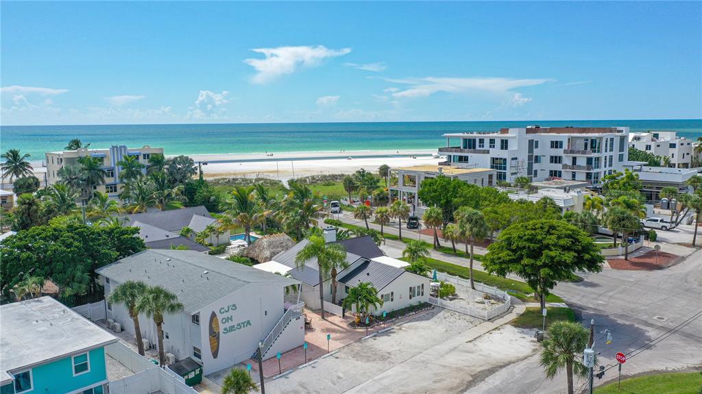 An aerial view shows a beachside property with a multi-story building and nearby coastal homes — 104 AVENIDA VENECCIA UNIT 171, SARASOTA, FL