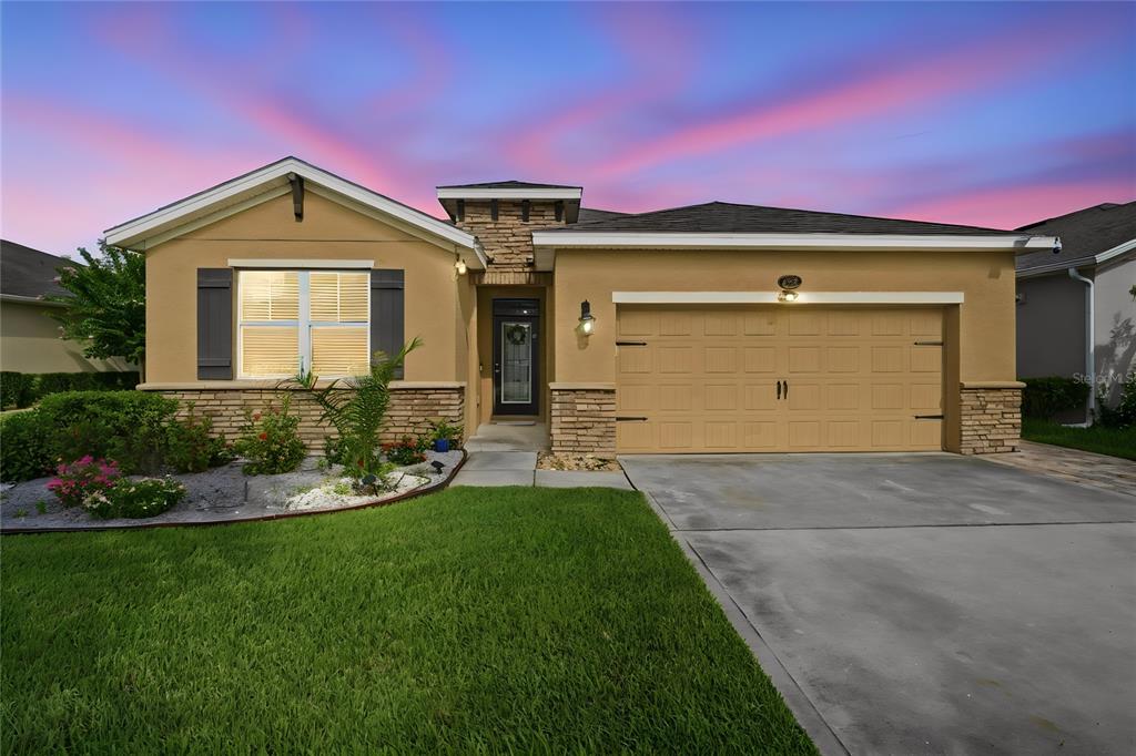 A single-story house with a tan stucco exterior, stone accents, and a two-car garage — 632 E VICTORIA TRAILS BOULEVARD, DELAND, FL