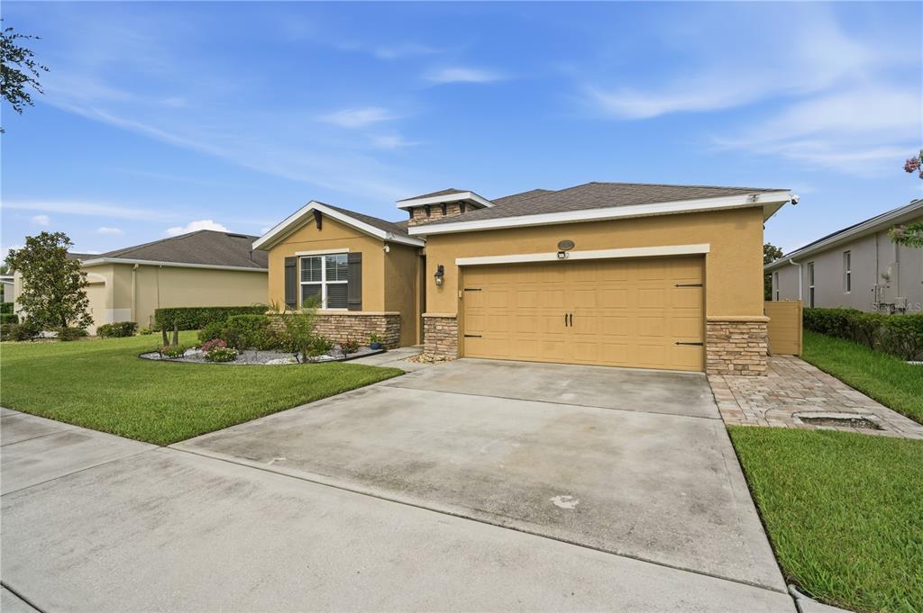 A single-story house with a tan stucco exterior, stone accents, and a two-car garage — 632 E VICTORIA TRAILS BOULEVARD, DELAND, FL