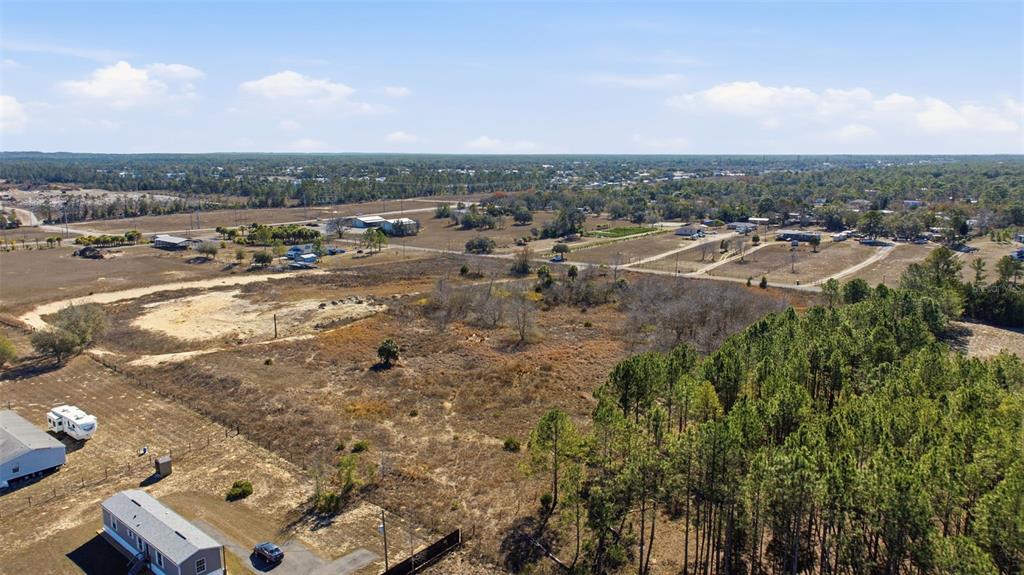 An aerial view shows a large, undeveloped grassy lot bordered by trees and nearby houses — SWEET GUM ROAD, BROOKSVILLE, FL