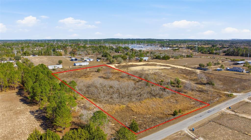 An aerial view shows a rectangular plot of vacant land outlined in red near a road — SWEET GUM ROAD, BROOKSVILLE, FL