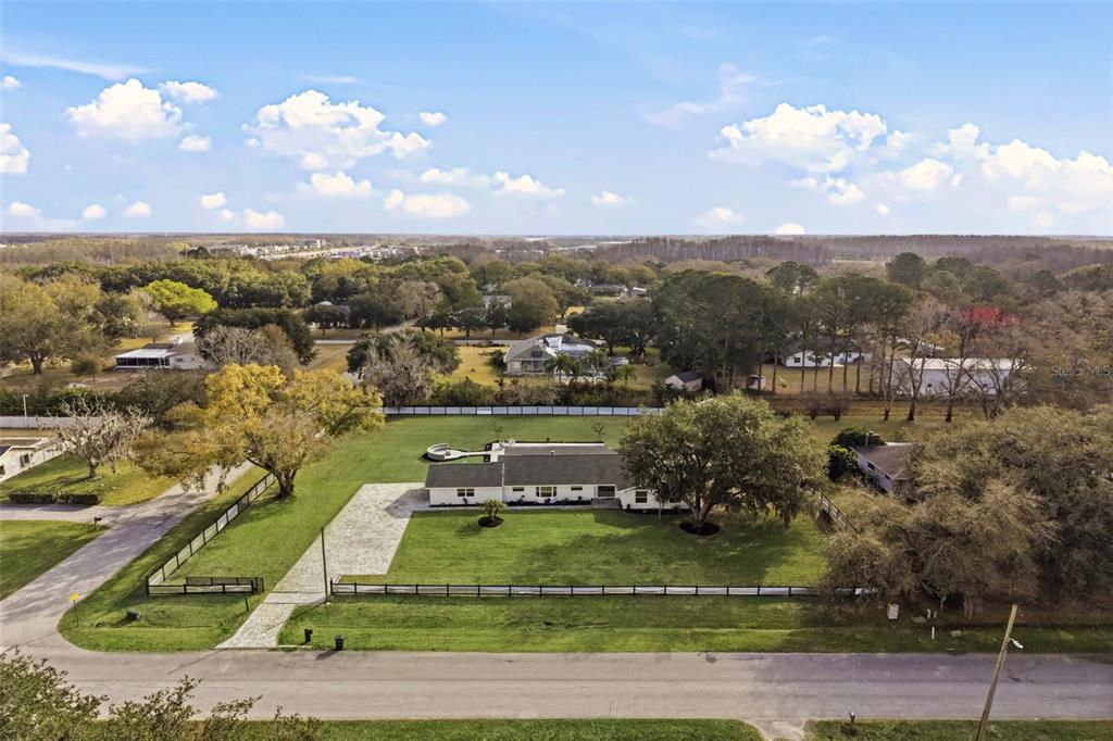 An aerial view shows a single-story house with a large lawn and fenced yard — 2338 MEADOWBROOK DRIVE, LUTZ, FL