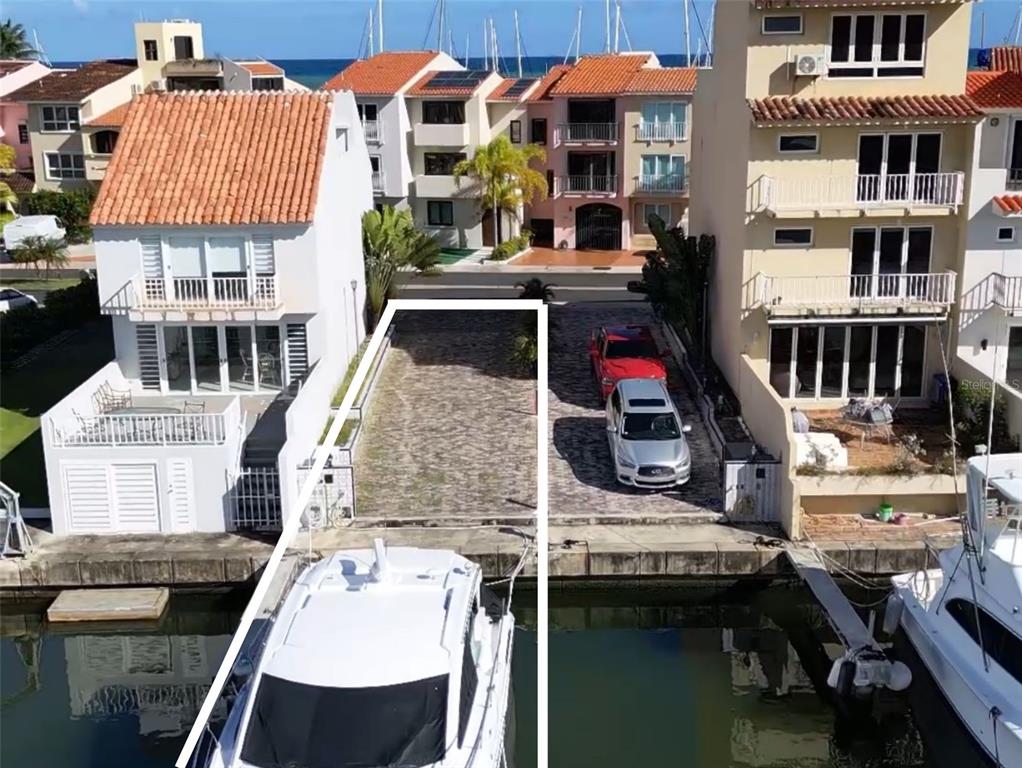 An aerial view shows a vacant paved lot situated between two multi-story waterfront townhomes — 9 ISLA SAN MIGUEL UNIT 9, HUMACAO, PR