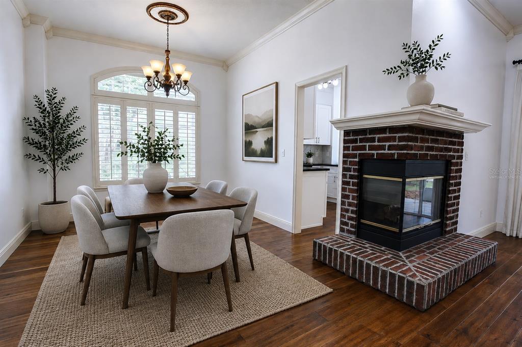 A dining room features a wooden table, upholstered chairs, a brick fireplace, and hardwood floors — 1257 BRAMPTON PLACE, LAKE MARY, FL