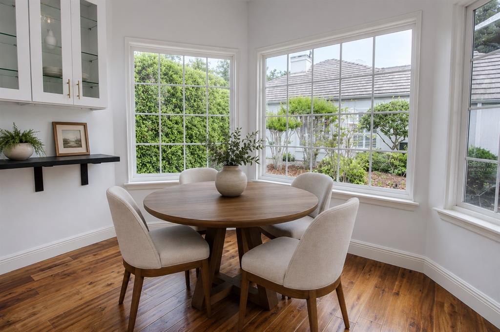 A dining nook features a round wooden table, four upholstered chairs, and large windows — 1257 BRAMPTON PLACE, LAKE MARY, FL