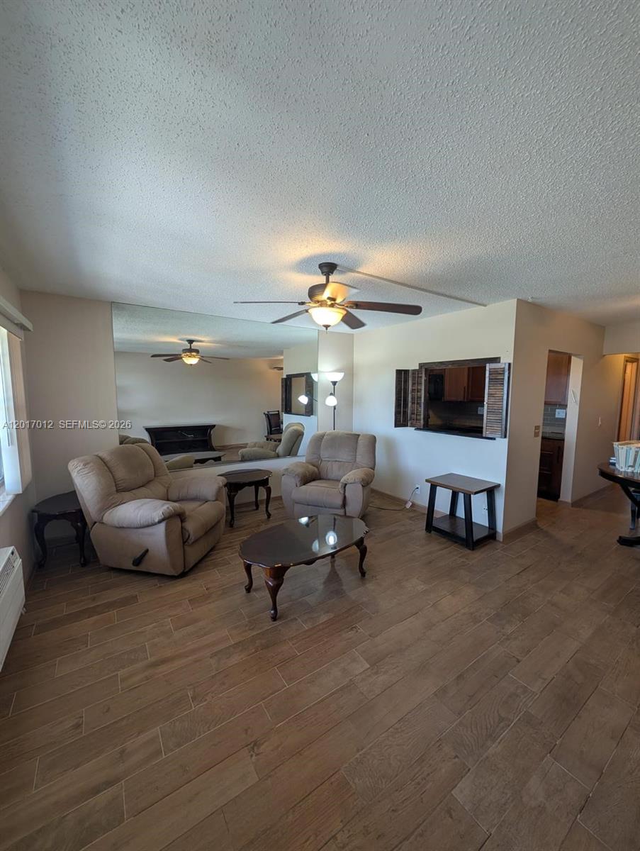 A living room features wood-look tile flooring, two beige armchairs, and a large wall mirror — 23 Easthampton A # 0, West Palm Beach FL 33417, WEST PALM BEACH, FL