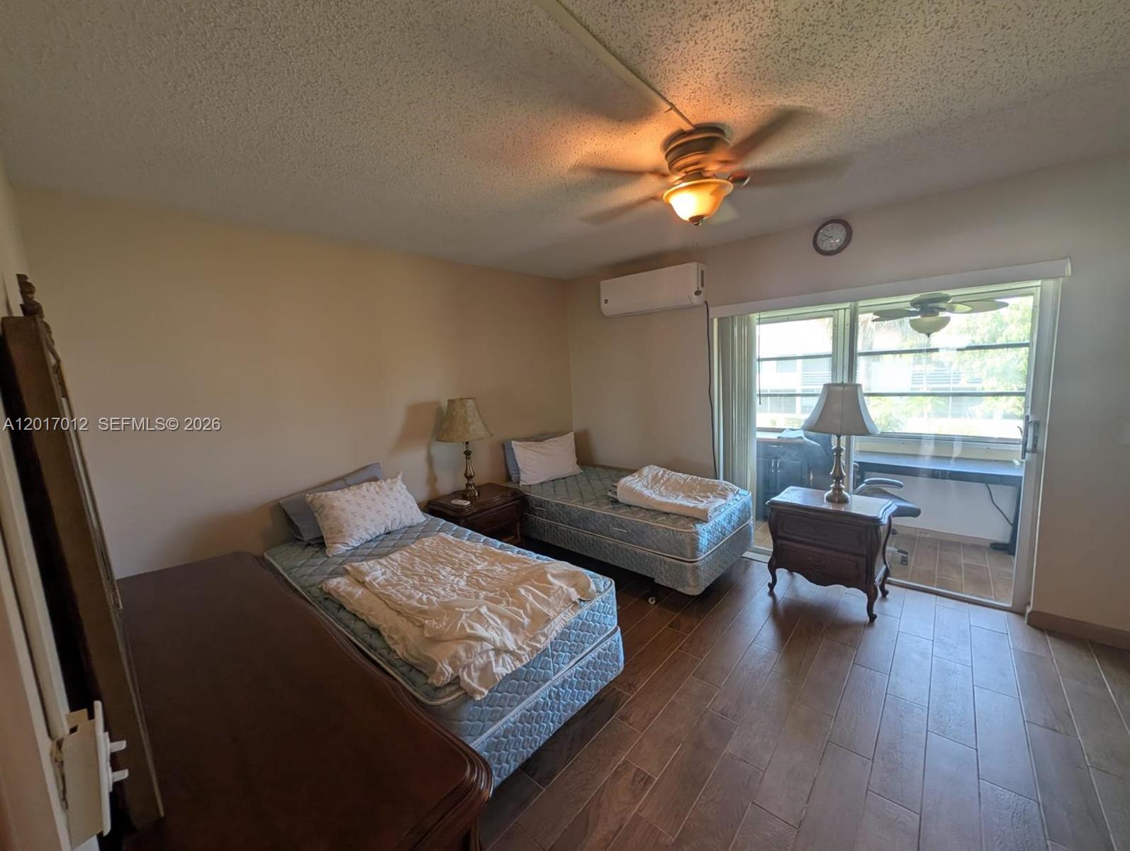 A bedroom features two twin beds, wood-look tile flooring, and a sliding glass door — 23 Easthampton A # 0, West Palm Beach FL 33417, WEST PALM BEACH, FL