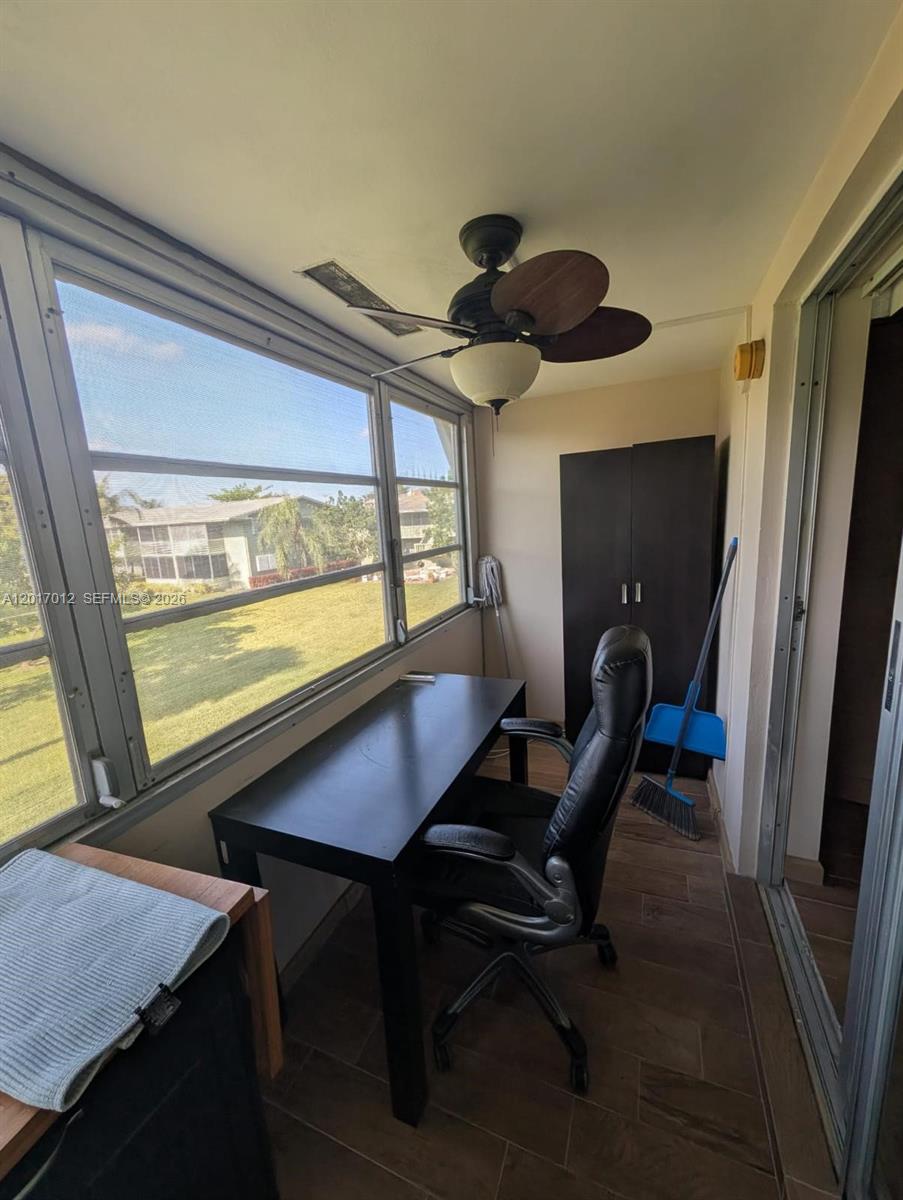 A sunroom features a desk, office chair, dark cabinet, ceiling fan, and large windows — 23 Easthampton A # 0, West Palm Beach FL 33417, WEST PALM BEACH, FL