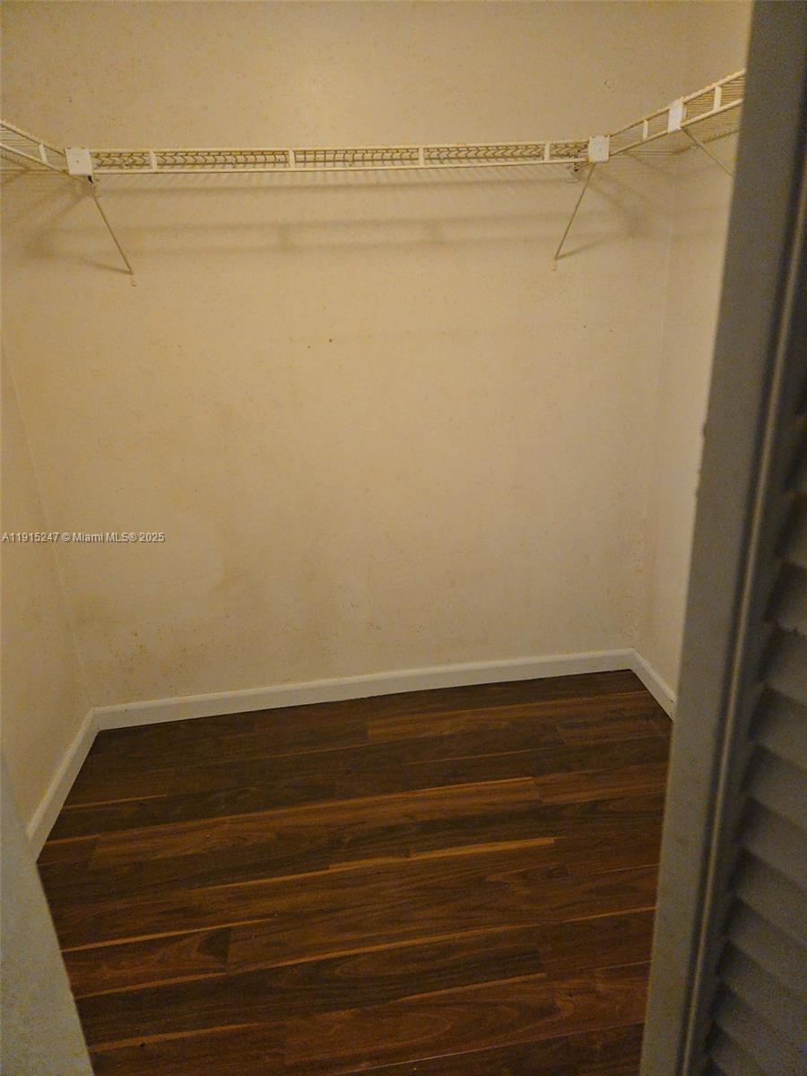 A walk-in closet features white wire shelving and dark wood-look flooring — 1524 NW 56th Ave # 7, Lauderhill FL 33313, LAUDERHILL, FL