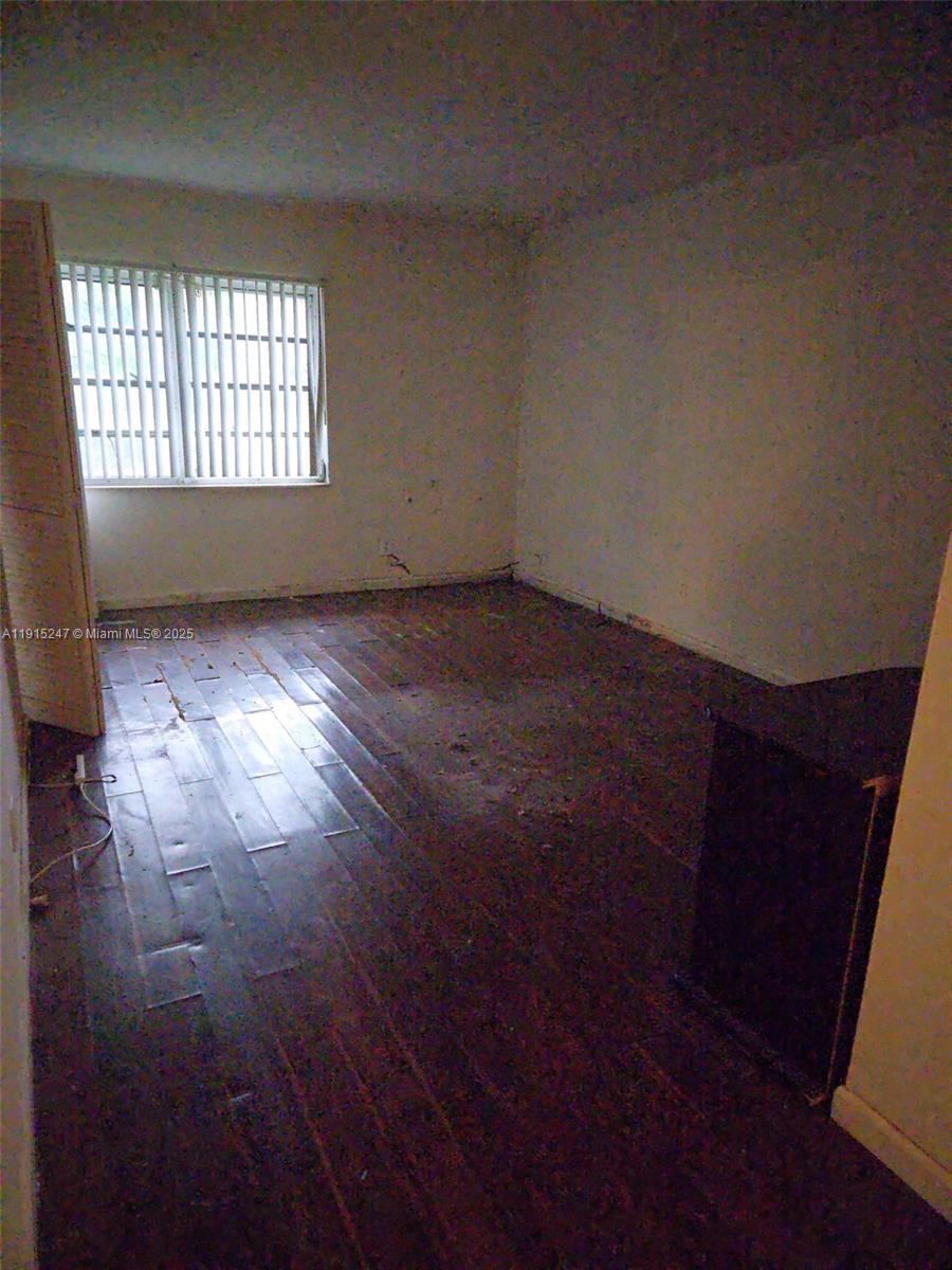 An empty room features dark wood-look flooring, white walls, and a window with vertical blinds — 1524 NW 56th Ave # 7, Lauderhill FL 33313, LAUDERHILL, FL