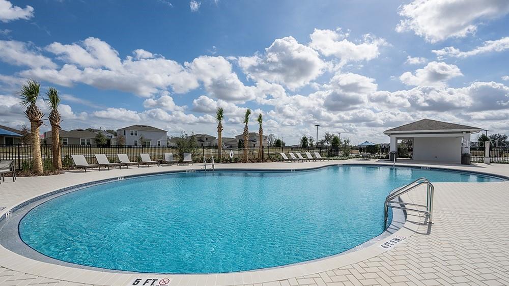 A swimming pool with lounge chairs and a covered pavilion under a cloudy sky — 228 STREAMWATER WAY, GROVELAND, FL