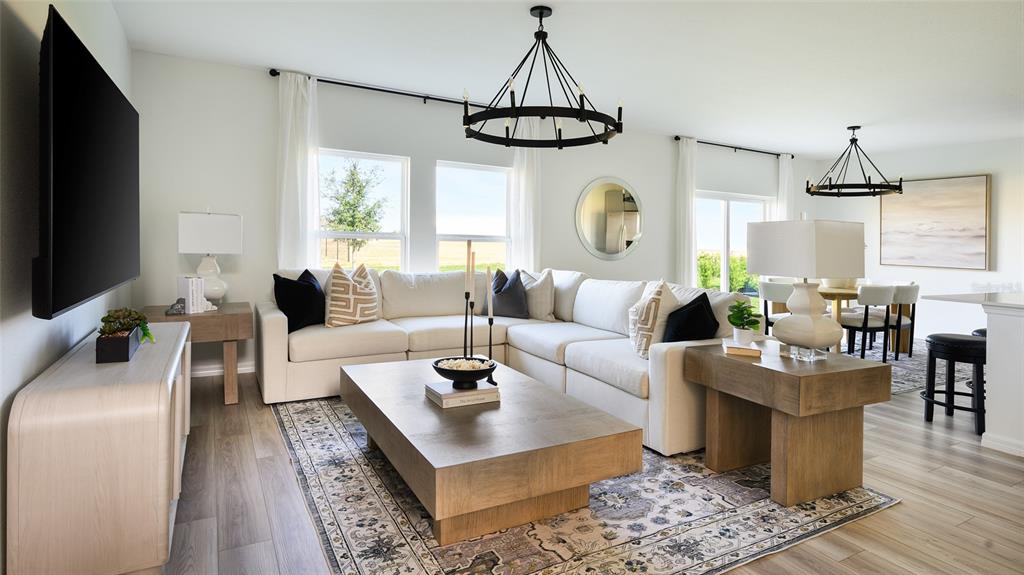 A bright living room features a large sectional sofa, wooden coffee table, and two chandeliers — 6043 PRAIRIE RUN, HAINES CITY, FL