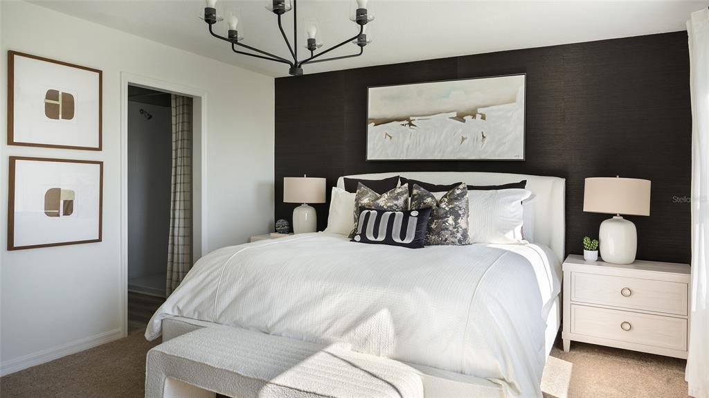 A bedroom features a white bed, a dark accent wall, and a modern chandelier — 6043 PRAIRIE RUN, HAINES CITY, FL