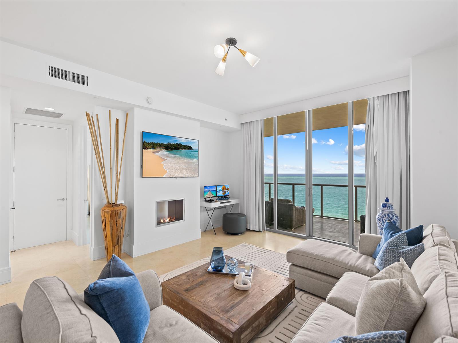 A living room features a fireplace, a television, and a balcony overlooking the ocean — 9705 Collins Avenue # 1104n, Bal Harbour FL 33154, BAL HARBOUR, FL