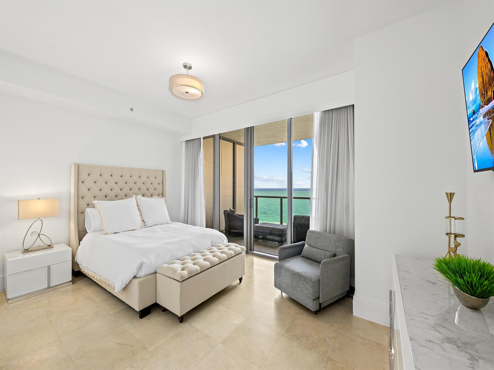 A bedroom with a tufted headboard, marble-topped furniture, and a balcony overlooking the ocean — 9705 Collins Avenue # 1104n, Bal Harbour FL 33154, BAL HARBOUR, FL