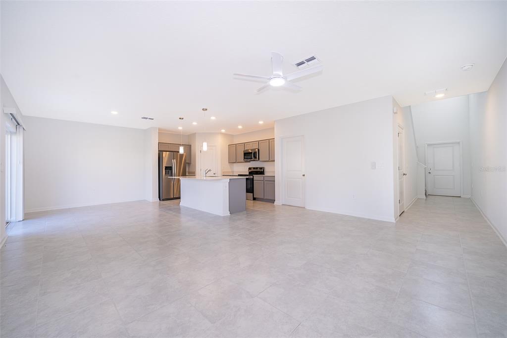 An open-concept kitchen and living area features light tile flooring, gray cabinetry, and an island — 2723 GENTLE RAIN DRIVE, DAVENPORT, FL