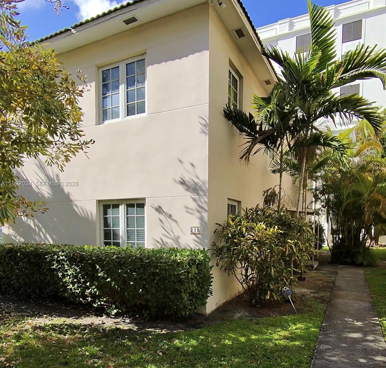 A two-story beige building with white-framed windows and a hedge in the front yard — 215 Sidonia Ave, Coral Gables FL 33134, CORAL GABLES, FL