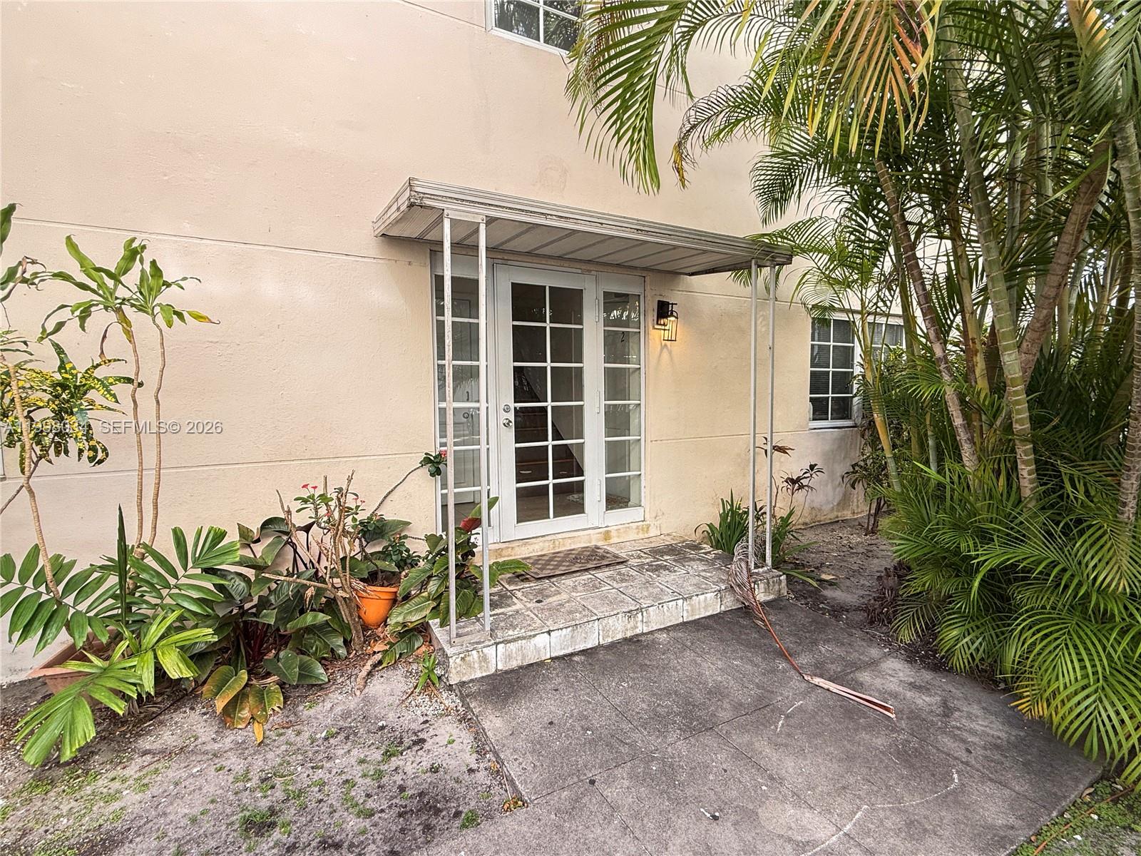 The exterior of a building features a white-framed glass door under a metal awning — 215 Sidonia Ave, Coral Gables FL 33134, CORAL GABLES, FL