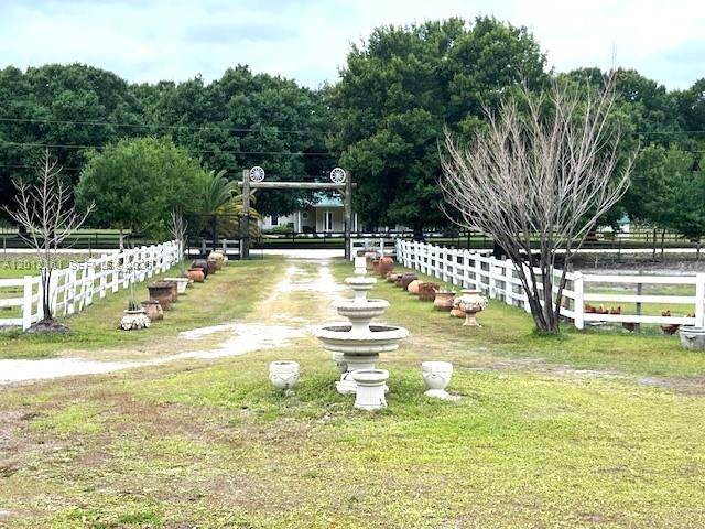 A gravel driveway leads through a white fence toward a house with a stone fountain — 2416 Vance Ave, Lorida FL 33857, LORIDA, FL