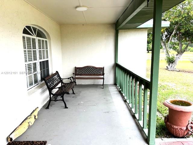 A covered porch features a concrete floor, two metal benches, and a large terracotta planter — 2416 Vance Ave, Lorida FL 33857, LORIDA, FL